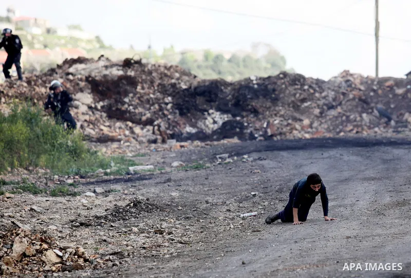 A Palestinian man rushes towards a boy who was injured during clashes with Israeli security forces following a demonstration against the expropriation of Palestinian land by Israel, in the village of Kfar Qaddum, near Na...
