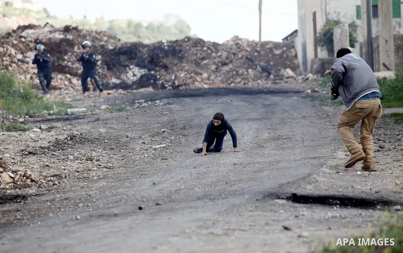 A Palestinian man rushes towards a boy who was injured during clashes with Israeli security forces following a demonstration against the expropriation of Palestinian land by Israel, in the village of Kfar Qaddum, near Na...