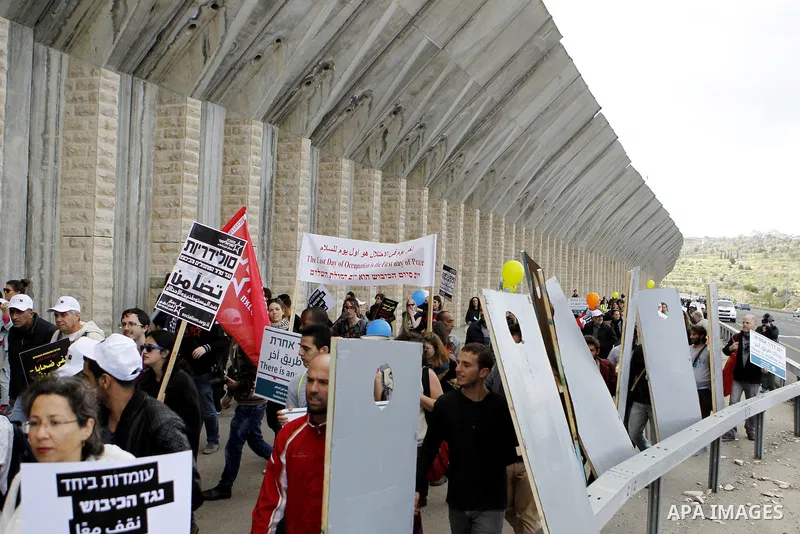 Peace activists hold placards during a joint Israeli-Palestinian peace march along the Israeli controvertial separation wall in the West Bank city of Beit Jala between Bethlehem and Jerusalem, on March 4, 2016. Peace act...