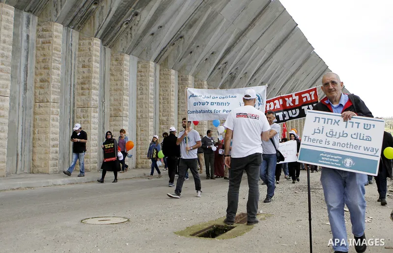 Peace activists hold placards during a joint Israeli-Palestinian peace march along the Israeli controvertial separation wall in the West Bank city of Beit Jala between Bethlehem and Jerusalem, on March 4, 2016. Peace act...