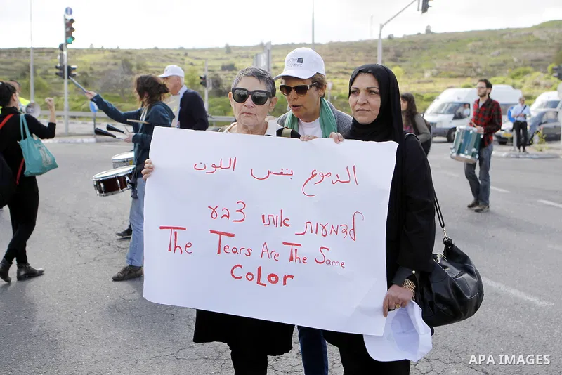 Peace activists hold placards during a joint Israeli-Palestinian peace march along the Israeli controvertial separation wall in the West Bank city of Beit Jala between Bethlehem and Jerusalem, on March 4, 2016. Peace act...