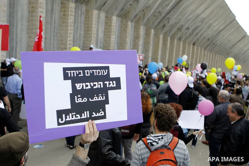 Peace activists hold placards during a joint Israeli-Palestinian peace march along the Israeli controvertial separation wall in the West Bank city of Beit Jala between Bethlehem and Jerusalem, on March 4, 2016. Peace act...