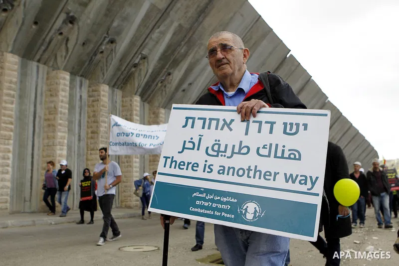 Peace activists hold placards during a joint Israeli-Palestinian peace march along the Israeli controvertial separation wall in the West Bank city of Beit Jala between Bethlehem and Jerusalem, on March 4, 2016. Peace act...