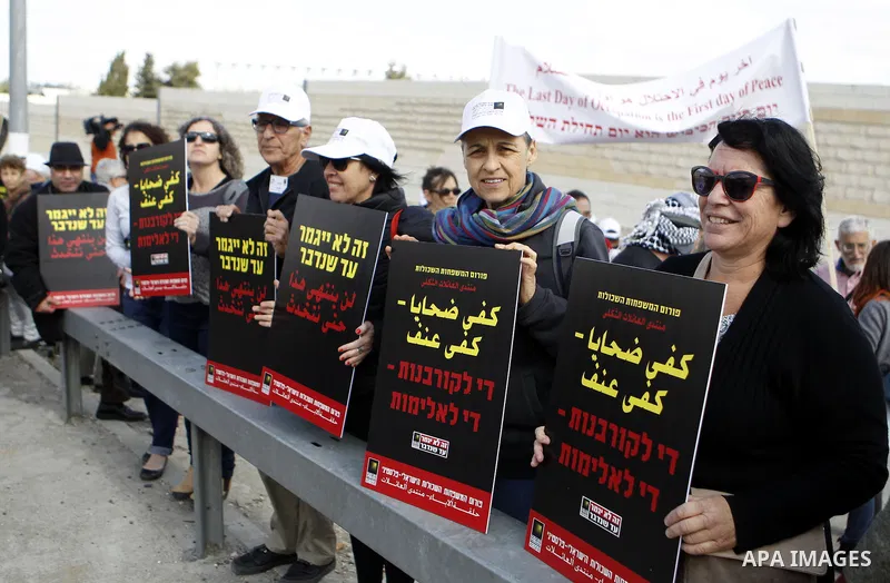 Peace activists hold placards during a joint Israeli-Palestinian peace march along the Israeli controvertial separation wall in the West Bank city of Beit Jala between Bethlehem and Jerusalem, on March 4, 2016. Peace act...