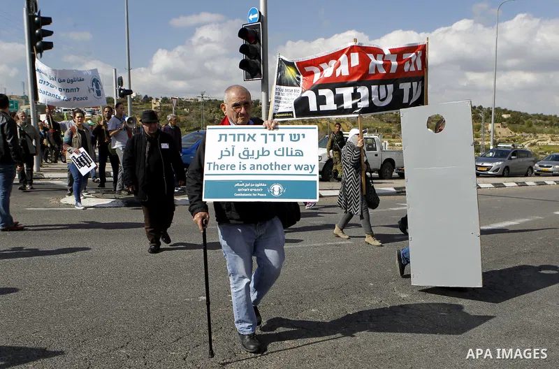 Peace activists hold placards during a joint Israeli-Palestinian peace march along the Israeli controvertial separation wall in the West Bank city of Beit Jala between Bethlehem and Jerusalem, on March 4, 2016. Peace act...