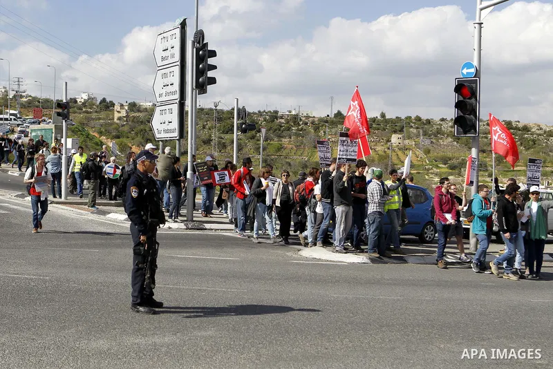 Peace activists hold placards during a joint Israeli-Palestinian peace march along the Israeli controvertial separation wall in the West Bank city of Beit Jala between Bethlehem and Jerusalem, on March 4, 2016. Peace act...