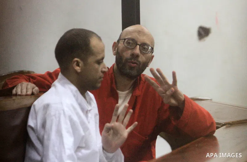 Defendants of Egyptian Muslim Brotherhood sit behind bars during the 'Qatar espionage' case, along with ousted Islamist president Mohamed Morsi (unseen) in a court in Cairo on March 06, 2016. The defendants are accused o...