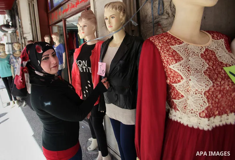 A Palestinian woman sells clothes at a shop, in the West Bank city of Nablus, on March 8, 2016. People around the globe celebrate International Women's Day, which dates back to the beginning of the 20th Century and has b...