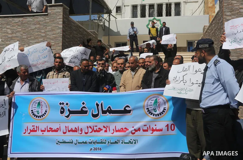 Palestinian laborers hold banners as they take part in a protest to demanding their rights, in front of the Legislative Council headquarters, in Gaza city, on March 10, 2016. Photo by Mohammed Asad