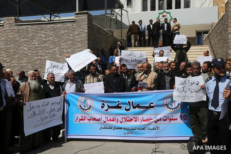 Palestinian laborers hold banners as they take part in a protest to demanding their rights, in front of the Legislative Council headquarters, in Gaza city, on March 10, 2016. Photo by Mohammed Asad
