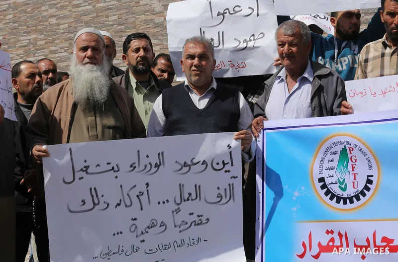 Palestinian laborers hold banners as they take part in a protest to demanding their rights, in front of the Legislative Council headquarters, in Gaza city, on March 10, 2016. Photo by Mohammed Asad