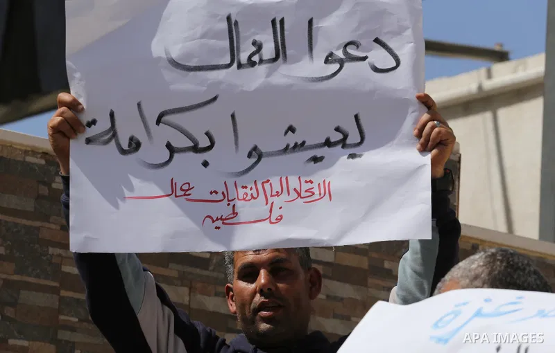 Palestinian laborers hold banners as they take part in a protest to demanding their rights, in front of the Legislative Council headquarters, in Gaza city, on March 10, 2016. Photo by Mohammed Asad