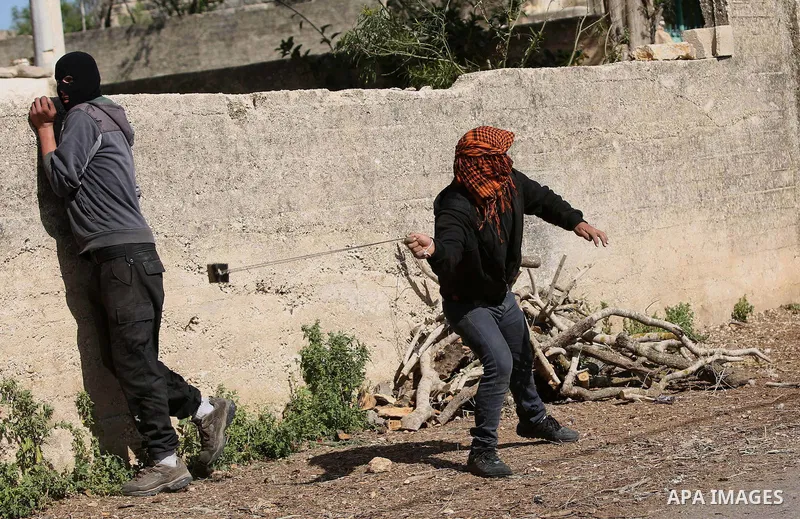 A Palestinian protester uses a slingshot to hurl stones toward Israeli security foces during clashes following a demonstration against the expropriation of Palestinian land by Israel in the village of Kfar Qaddum, near N...