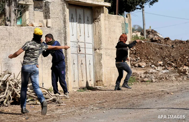 Palestinian protesters use a slingshot to hurl stones toward Israeli security foces during clashes following a demonstration against the expropriation of Palestinian land by Israel in the village of Kfar Qaddum, near Nab...