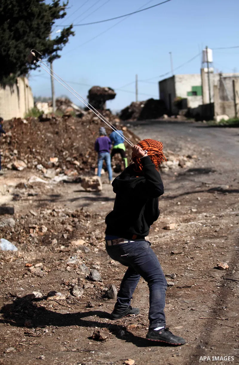 A Palestinian protester uses a slingshot to hurl stones toward Israeli security foces during clashes following a demonstration against the expropriation of Palestinian land by Israel in the village of Kfar Qaddum, near N...