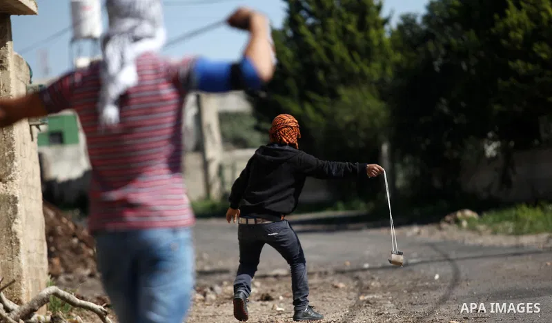 Palestinian protesters use a slingshot to hurl stones toward Israeli security foces during clashes following a demonstration against the expropriation of Palestinian land by Israel in the village of Kfar Qaddum, near Nab...