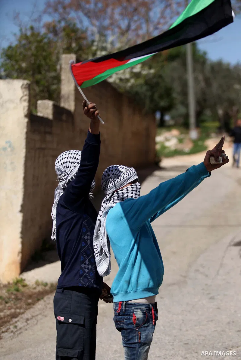 A Palestinian protester hold a national flag during clashes with Israeli secuirty forces following a demonstration against the expropriation of Palestinian land by Israel in the village of Kfar Qaddum, near Nablus, in th...