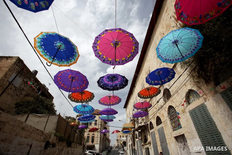 A picture taken on March 13, 2016 shows umbrellas used to decorate a street in the old city of Nablus, in the occupied West Bank. Photo by Nedal Eshtayah
