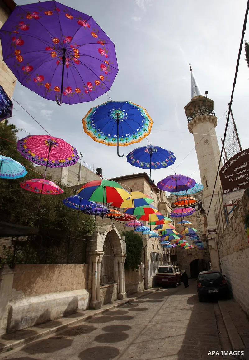 A picture taken on March 13, 2016 shows umbrellas used to decorate a street in the old city of Nablus, in the occupied West Bank. Photo by Nedal Eshtayah