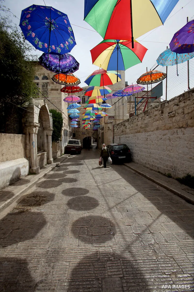 A picture taken on March 13, 2016 shows umbrellas used to decorate a street in the old city of Nablus, in the occupied West Bank. Photo by Nedal Eshtayah