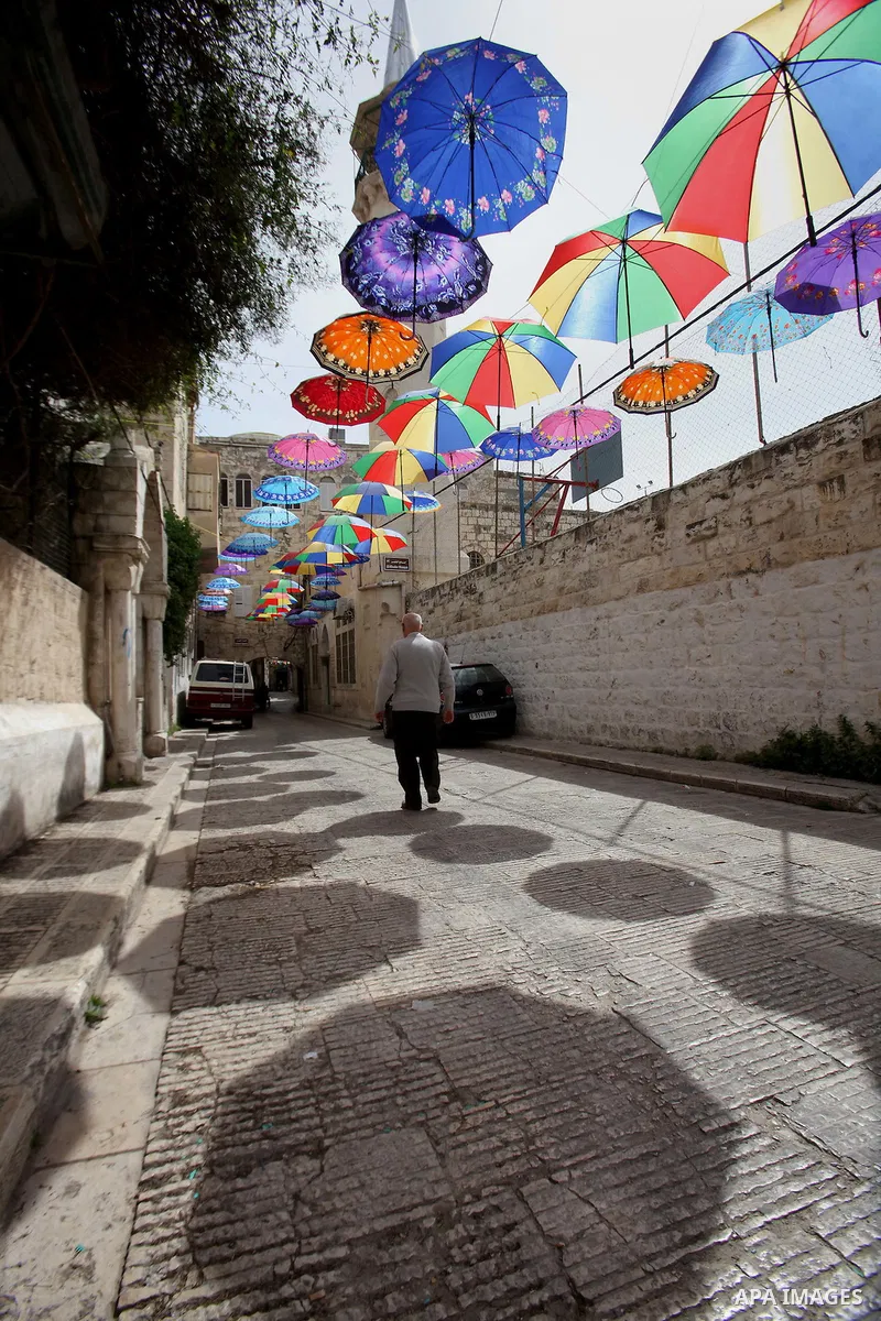 A picture taken on March 13, 2016 shows umbrellas used to decorate a street in the old city of Nablus, in the occupied West Bank. Photo by Nedal Eshtayah