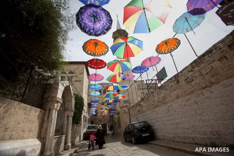 A picture taken on March 13, 2016 shows umbrellas used to decorate a street in the old city of Nablus, in the occupied West Bank. Photo by Nedal Eshtayah