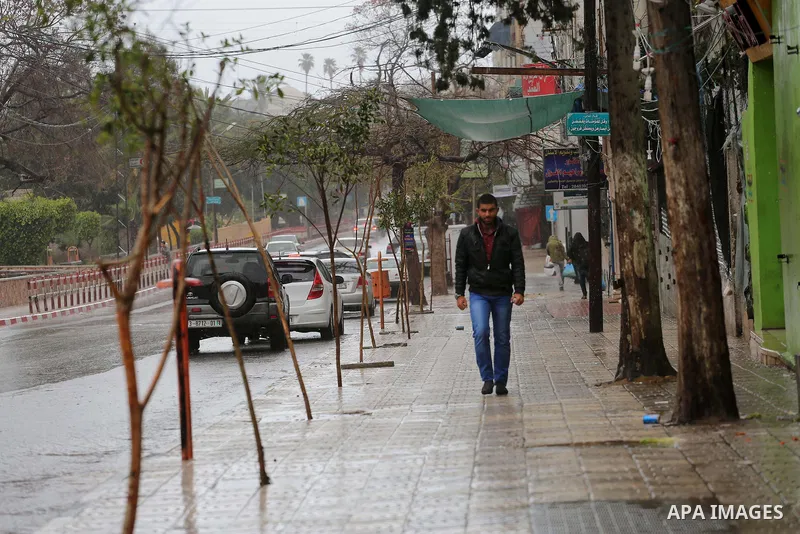 Palestinians walk in a street flooded by rain water, in Gaza city, on March 16, 2016. Photo by Mohammed Asad