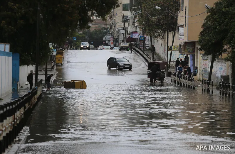 Palestinians walk in a street flooded by rain water, in Gaza city, on March 16, 2016. Photo by Mohammed Asad