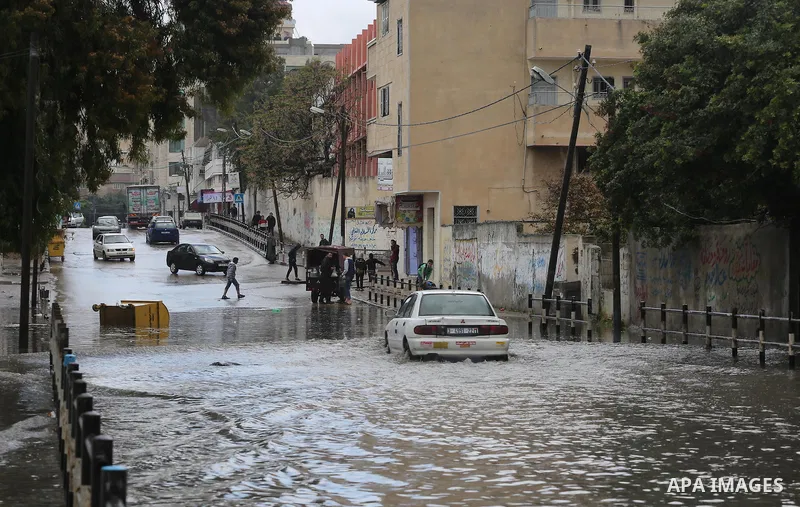 Palestinians walk in a street flooded by rain water, in Gaza city, on March 16, 2016. Photo by Mohammed Asad