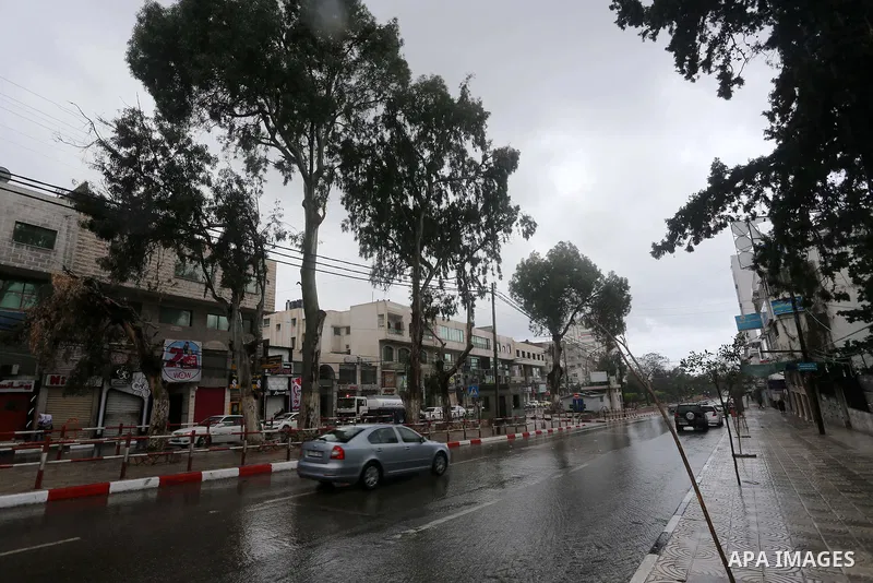 Palestinians walk in a street flooded by rain water, in Gaza city, on March 16, 2016. Photo by Mohammed Asad