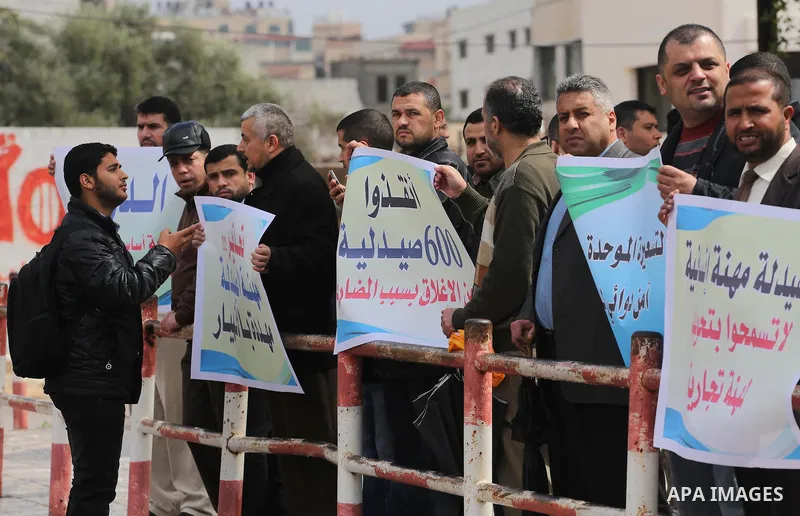 Palestinian pharmacists hold banners during a protest against the pricing treatment in front of the Legislative Council, in Gaza city, on March 16, 2016. Photo by Mohammed Asad