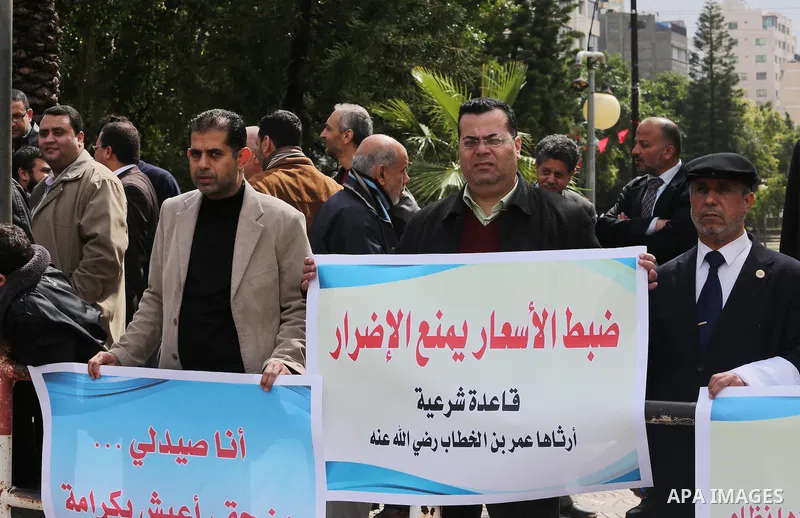Palestinian pharmacists hold banners during a protest against the pricing treatment in front of the Legislative Council, in Gaza city, on March 16, 2016. Photo by Mohammed Asad