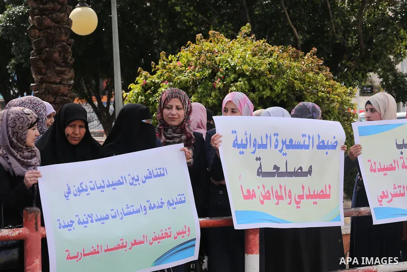 Palestinian pharmacists hold banners during a protest against the pricing treatment in front of the Legislative Council, in Gaza city, on March 16, 2016. Photo by Mohammed Asad