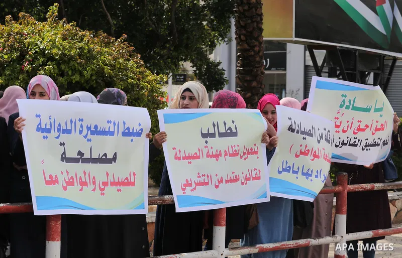 Palestinian pharmacists hold banners during a protest against the pricing treatment in front of the Legislative Council, in Gaza city, on March 16, 2016. Photo by Mohammed Asad