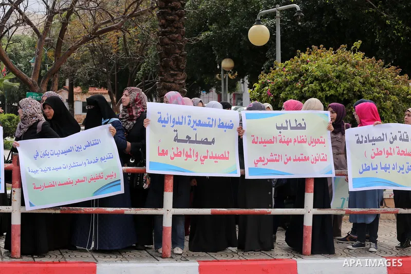 Palestinian pharmacists hold banners during a protest against the pricing treatment in front of the Legislative Council, in Gaza city, on March 16, 2016. Photo by Mohammed Asad