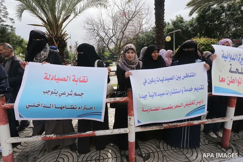 Palestinian pharmacists hold banners during a protest against the pricing treatment in front of the Legislative Council, in Gaza city, on March 16, 2016. Photo by Mohammed Asad