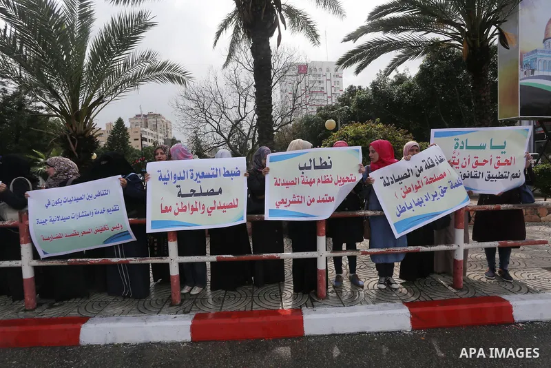 Palestinian pharmacists hold banners during a protest against the pricing treatment in front of the Legislative Council, in Gaza city, on March 16, 2016. Photo by Mohammed Asad