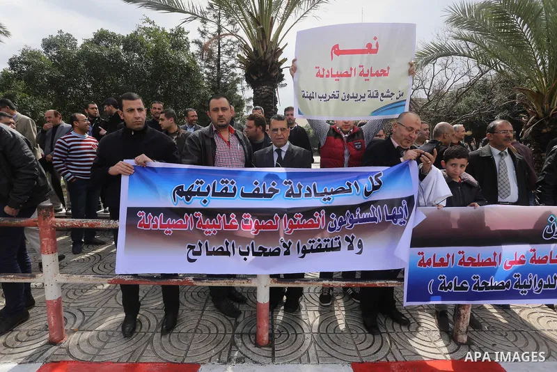 Palestinian pharmacists hold banners during a protest against the pricing treatment in front of the Legislative Council, in Gaza city, on March 16, 2016. Photo by Mohammed Asad