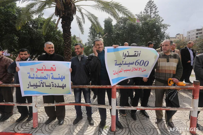 Palestinian pharmacists hold banners during a protest against the pricing treatment in front of the Legislative Council, in Gaza city, on March 16, 2016. Photo by Mohammed Asad
