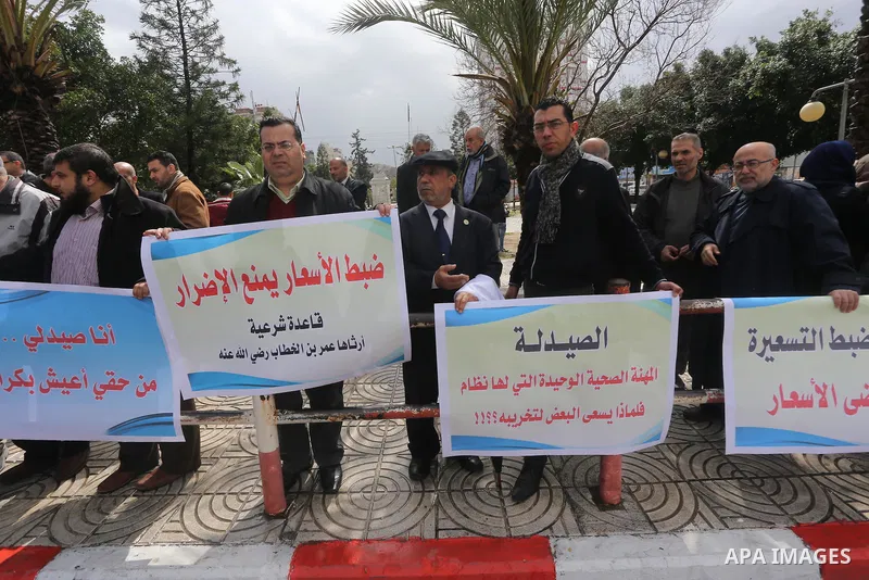 Palestinian pharmacists hold banners during a protest against the pricing treatment in front of the Legislative Council, in Gaza city, on March 16, 2016. Photo by Mohammed Asad