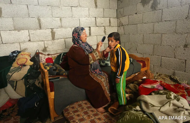 Palestinian woman Jihan Abu Muhsen sits inside her dwelling before going to work collecting bricks for sale from the sites of demolished buildings in Khan Younis in the southern Gaza Strip March 17, 2016. Abu Muhsen gath...