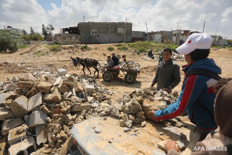 Palestinian woman Jihan Abu Muhsen collects bricks for sale with her son Mohammad from the ruins of a house destroyed during the 2014 war in Khan Younis in the southern Gaza Strip March 17, 2016. Abu Muhsen gathers brick...