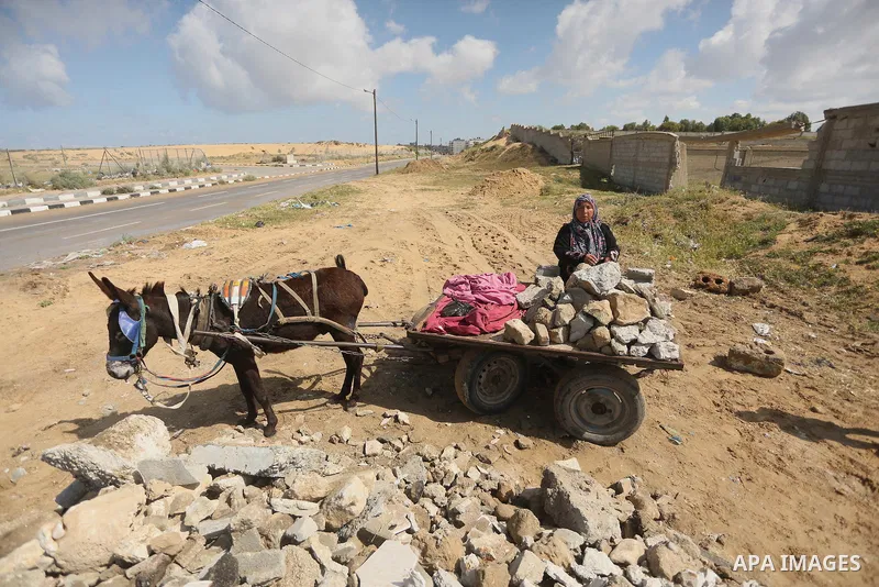 Palestinian woman Jihan Abu Muhsen collects bricks for sale with her son Mohammad from the ruins of a house destroyed during the 2014 war in Khan Younis in the southern Gaza Strip March 17, 2016. Abu Muhsen gathers brick...