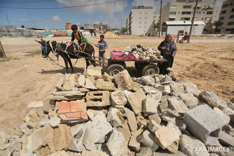 Palestinian woman Jihan Abu Muhsen collects bricks for sale with her son Mohammad from the ruins of a house destroyed during the 2014 war in Khan Younis in the southern Gaza Strip March 17, 2016. Abu Muhsen gathers brick...