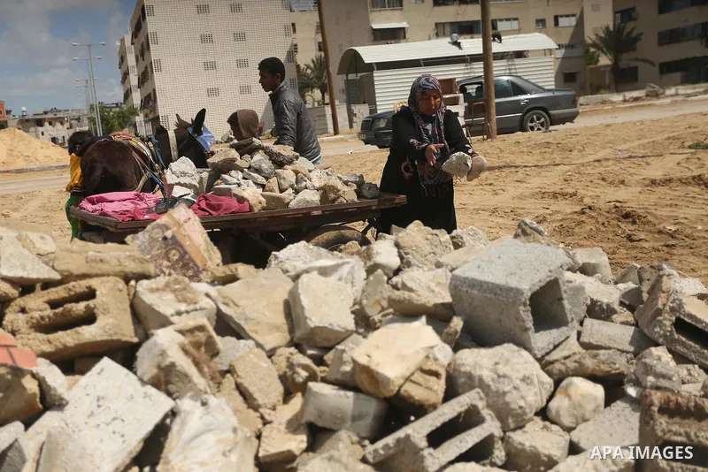 Palestinian woman Jihan Abu Muhsen collects bricks for sale with her son Mohammad from the ruins of a house destroyed during the 2014 war in Khan Younis in the southern Gaza Strip March 17, 2016. Abu Muhsen gathers brick...