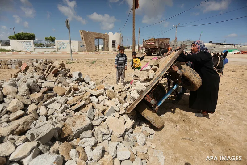 Palestinian woman Jihan Abu Muhsen collects bricks for sale with her son Mohammad from the ruins of a house destroyed during the 2014 war in Khan Younis in the southern Gaza Strip March 17, 2016. Abu Muhsen gathers brick...