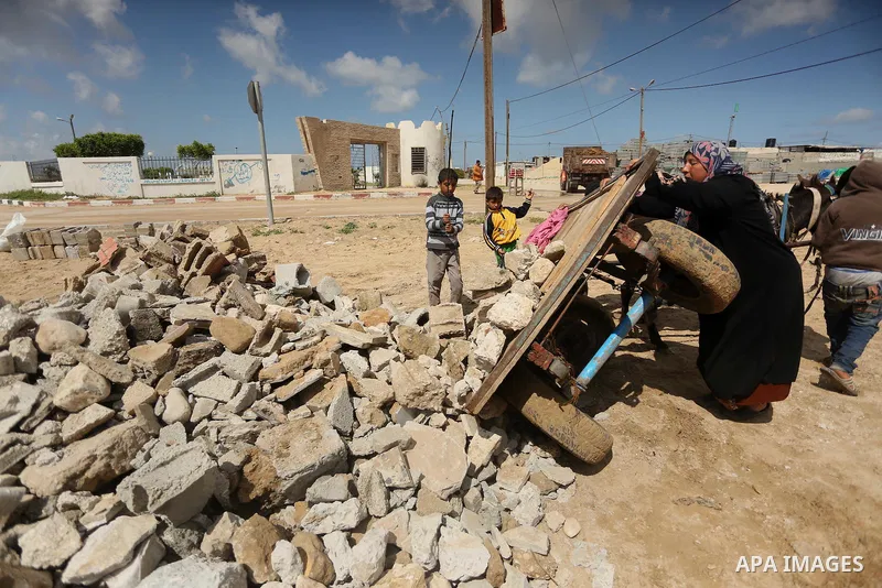 Palestinian woman Jihan Abu Muhsen collects bricks for sale with her son Mohammad from the ruins of a house destroyed during the 2014 war in Khan Younis in the southern Gaza Strip March 17, 2016. Abu Muhsen gathers brick...