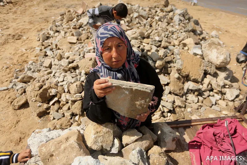 Palestinian woman Jihan Abu Muhsen collects bricks for sale with her son Mohammad from the ruins of a house destroyed during the 2014 war in Khan Younis in the southern Gaza Strip March 17, 2016. Abu Muhsen gathers brick...