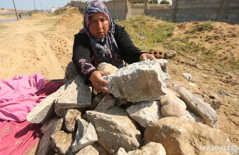 Palestinian woman Jihan Abu Muhsen collects bricks for sale with her son Mohammad from the ruins of a house destroyed during the 2014 war in Khan Younis in the southern Gaza Strip March 17, 2016. Abu Muhsen gathers brick...