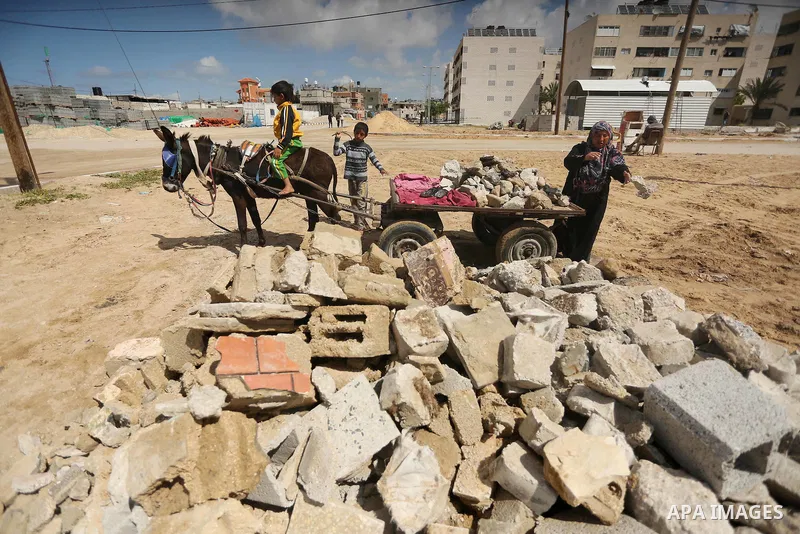 Palestinian woman Jihan Abu Muhsen collects bricks for sale with her son Mohammad from the ruins of a house destroyed during the 2014 war in Khan Younis in the southern Gaza Strip March 17, 2016. Abu Muhsen gathers brick...
